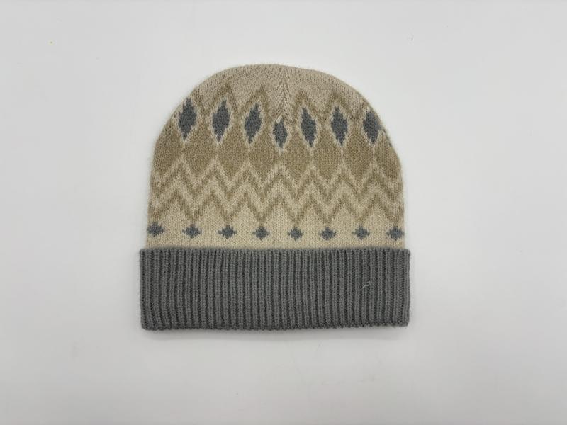 Beżowa czapka beanie z szarym wzorem Fair Isle w romby i zygzaki oraz szarym prążkowanym mankietem, na białym tle.