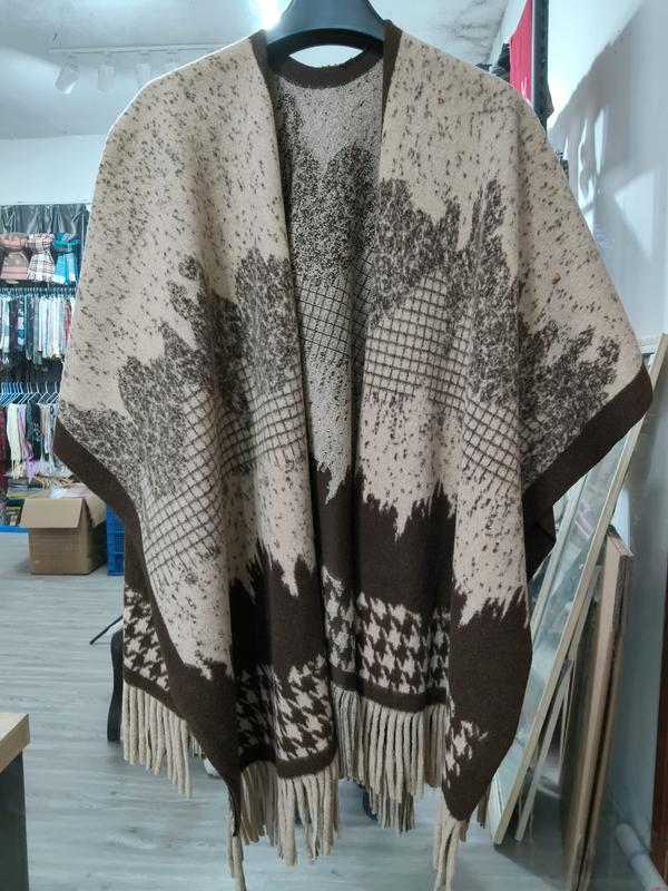 Ponczo cape w beżowo-brązowe liście, wzór pepitki, frędzle u dołu, na wieszaku.