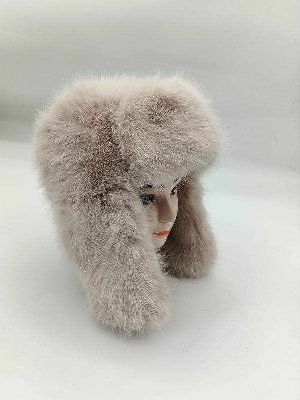 Puszysta czapka uszanka beżowa ze sztucznego futra z długimi nausznikami na manekinie, białe tło.