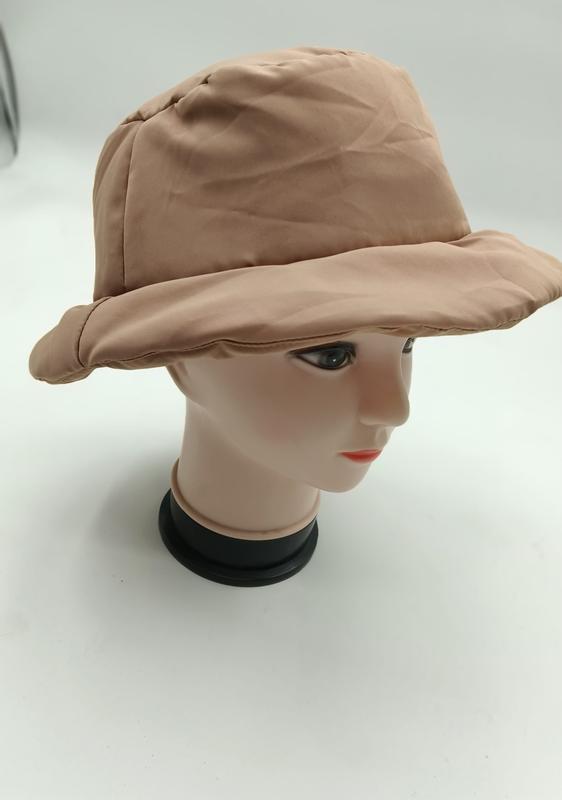 Beżowy pikowany kapelusz bucket hat z szerokim rondem i nylonową watowaną tkaniną na głowie manekina.