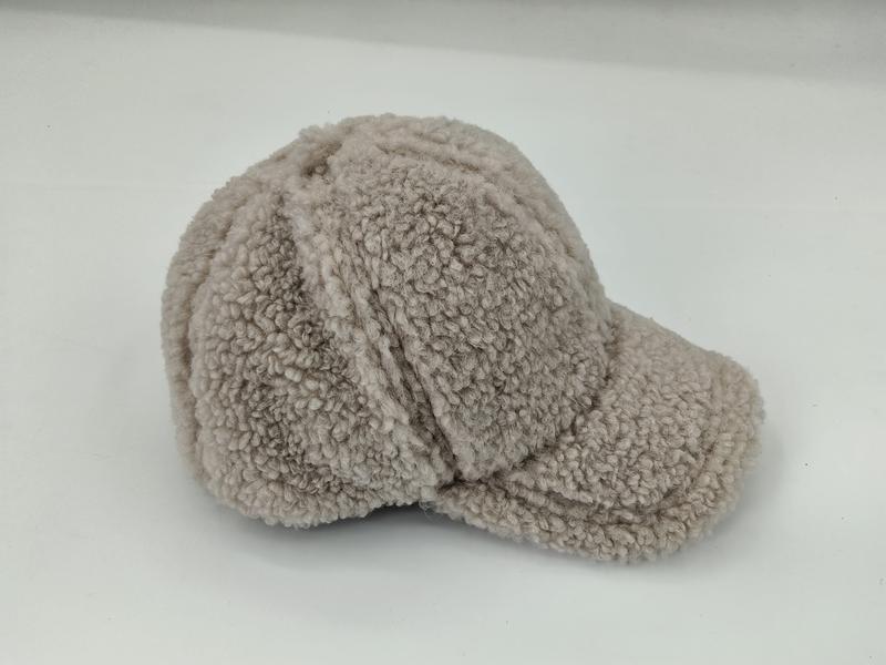 Beżowa czapka z daszkiem z miękkiego materiału sherpa, ze sztywnym daszkiem i szwami na panelach.