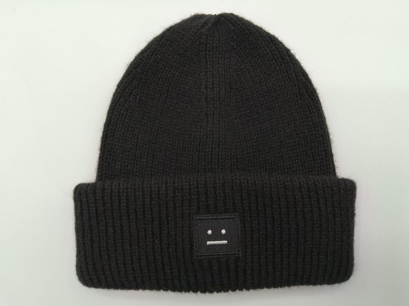 Czarna prążkowana czapka beanie z zawiniętym mankietem i wyszywaną naszywką z motywem twarzy.