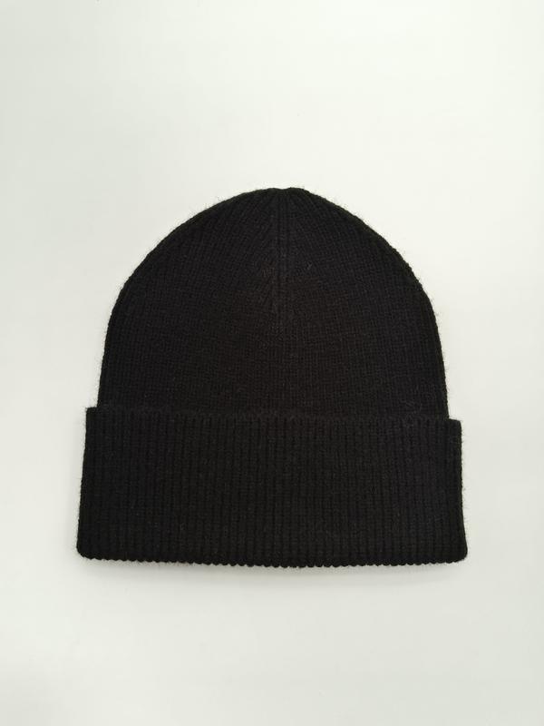 Czarna prążkowana czapka beanie z podwiniętym mankietem, ułożona płasko na białym tle, miękka wełniana czapka zimowa.