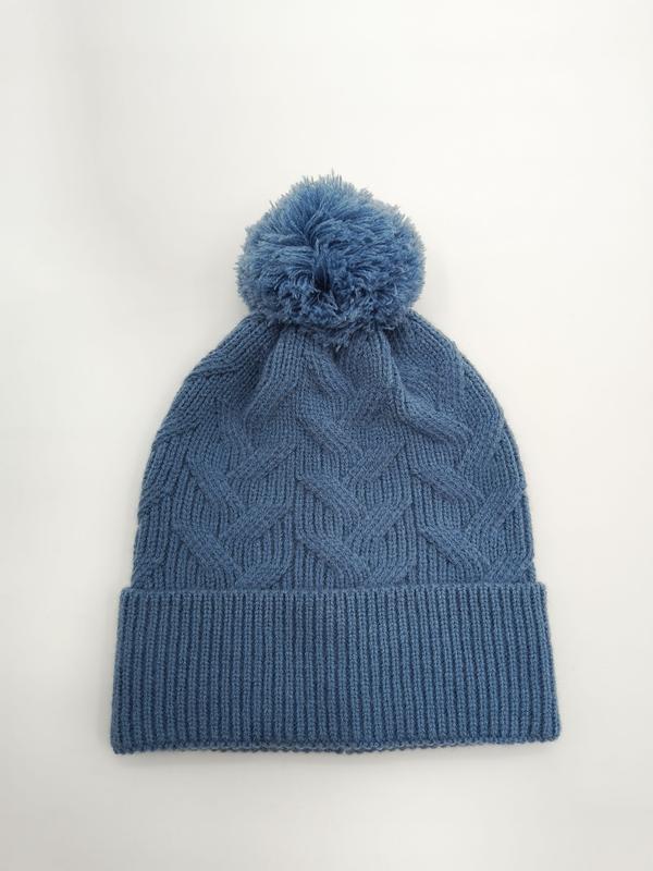 Stalowoniebieska czapka zimowa beanie z warkoczowym splotem, puszystym pomponem i ściągaczem, na białym tle.