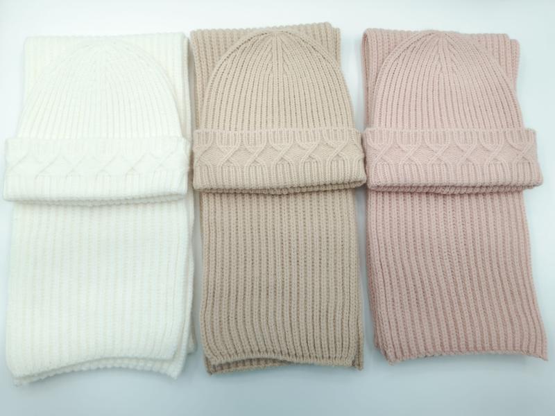 Trzy zestawy czapka beanie i szalik w splocie warkoczowym: ecru, taupe i bladoróżowy, na białym tle.