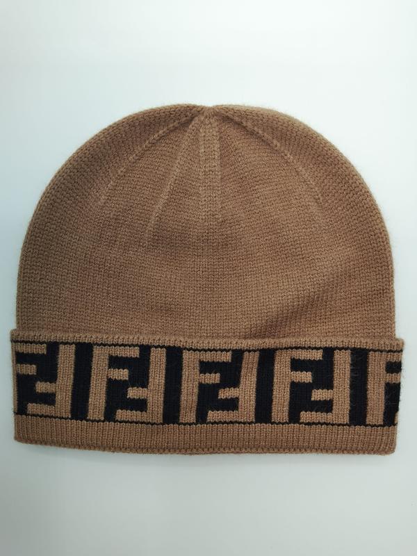 Beżowa czapka beanie z drobnego dzianiny ze zwiniętym mankietem z czarnym geometrycznym wzorem monogramu.