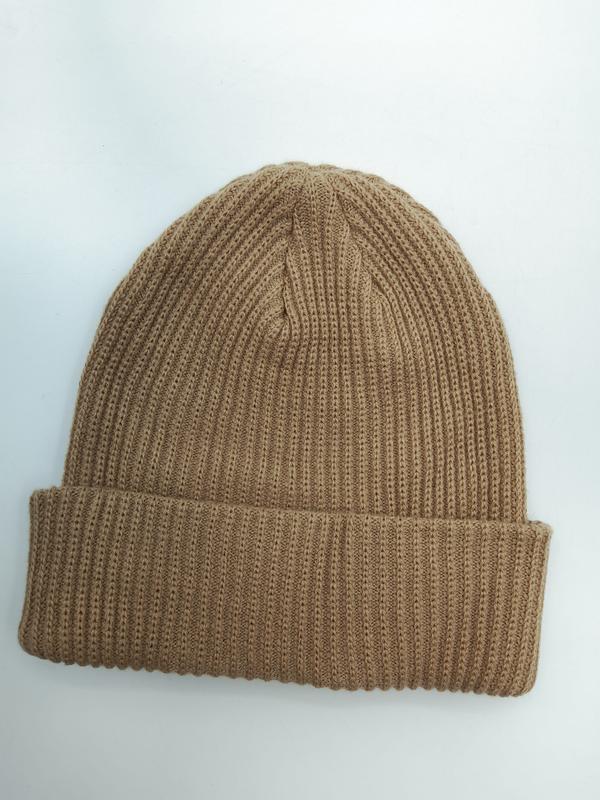 Beżowa czapka beanie z prążkowanej dzianiny z podwiniętym mankietem, ułożona płasko na białym tle.