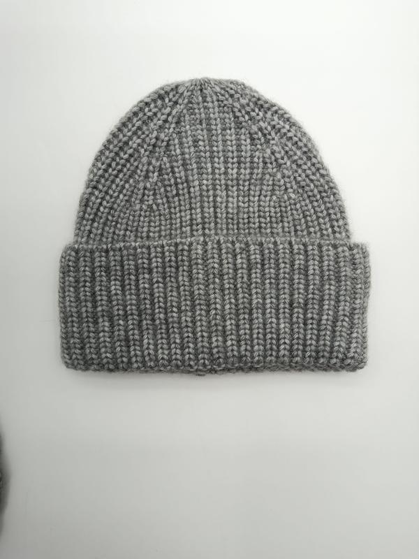Szara czapka beanie z grubym prążkowanym splotem i podwiniętym mankietem, leżąca płasko na białym tle.