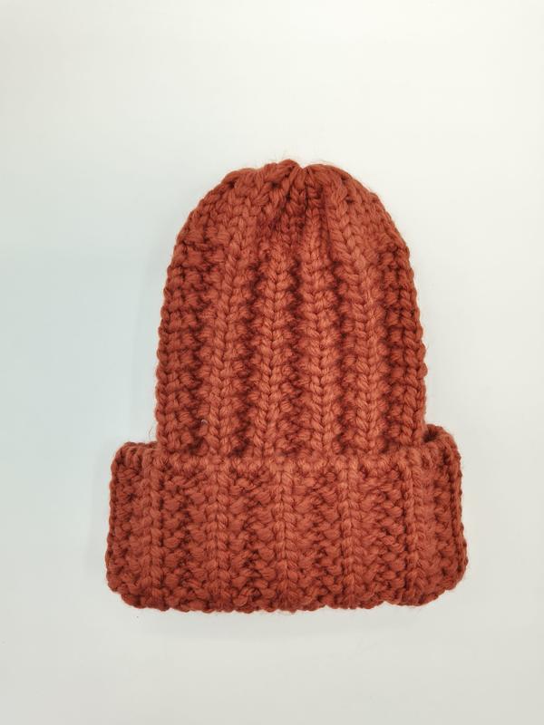 Rdzawopomarańczowa czapka beanie z grubym prążkowanym splotem i podwiniętym mankietem, ręcznie robiona z wełny.