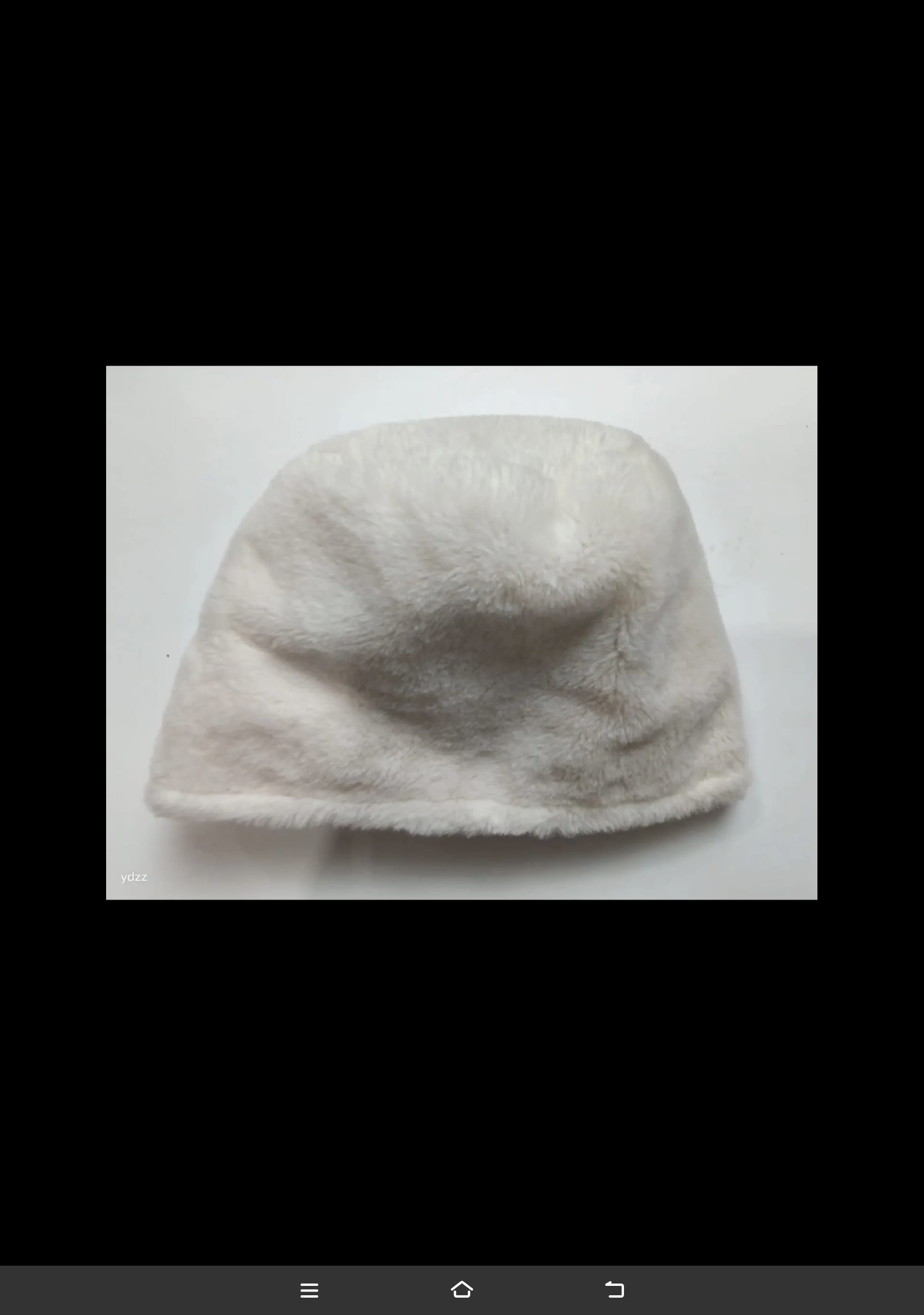 Kremowy bucket hat z sztucznego futra, miękka i puszysta czapka zimowa, widok z góry na białym tle.