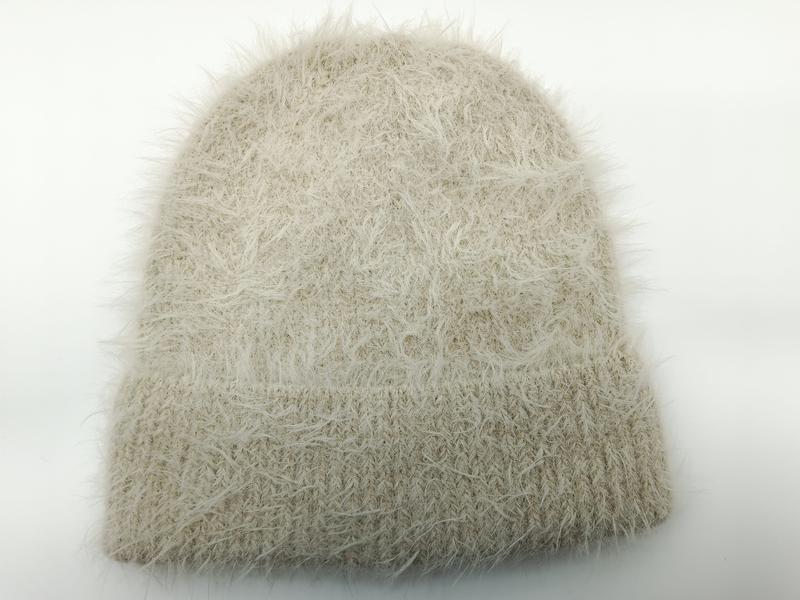 Kremowa czapka beanie z włóczki eyelash z prążkowanym mankietem na białym tle.