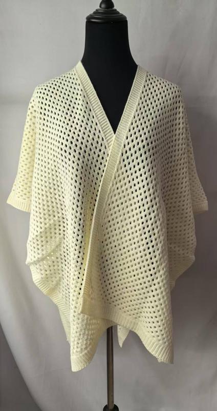 Kremowe kimono kardigan z ażurowym splotem, prezentowane na czarnym manekinie z драпowanym przodem.