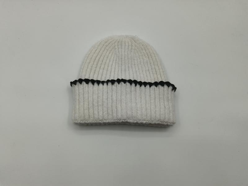 Kremowa czapka beanie z grubym prążkowanym splotem, podwijanym mankietem i czarnym kontrastowym ściegiem.