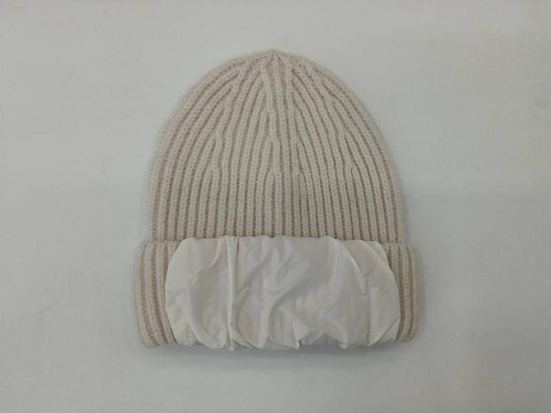 Kremowa prążkowana czapka zimowa beanie z puszystym mankietem, płasko ułożona na białym tle.