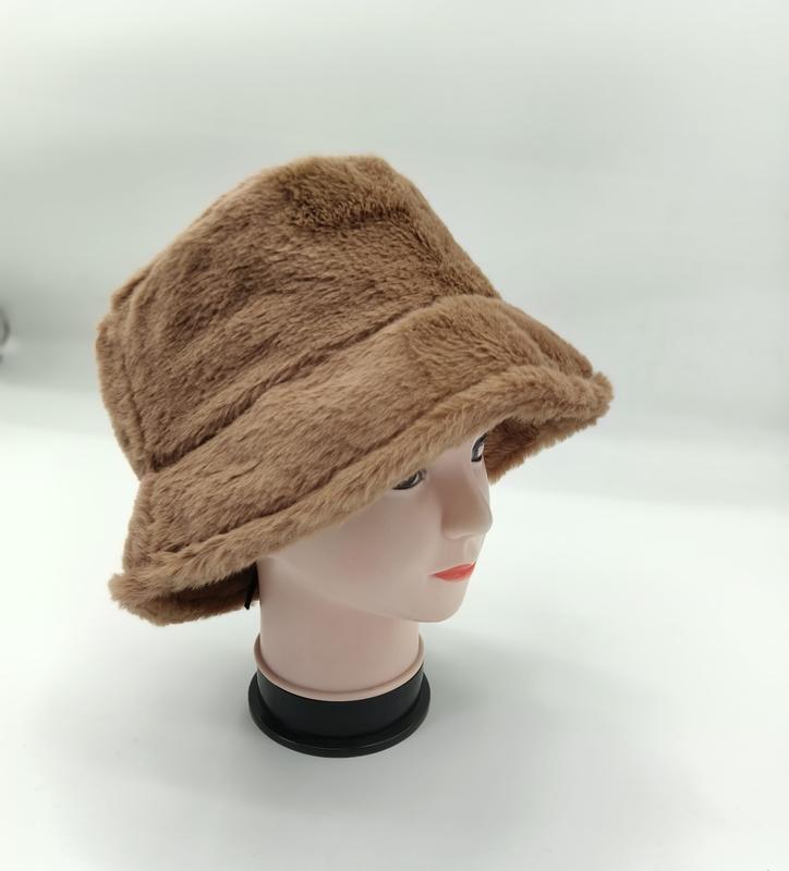 Brązowy kapelusz bucket hat z ekologicznego futra na manekinie, puszysty z szerokim rondem, idealny na zimę.