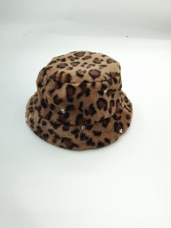 Puszysta czapka bucket hat w panterkę w odcieniach beżu i brązu z kryształkowymi zdobieniami na białym tle.