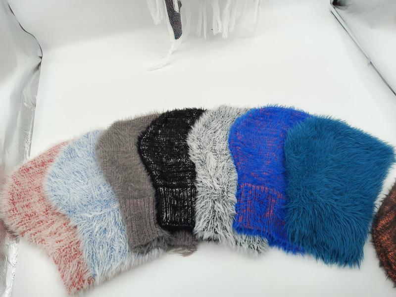 Sześć puszystych czapek beanie w kolorach: różowym, niebieskim, szarym, czarnym, białym i granatowym, ułożonych wachlarzowo.