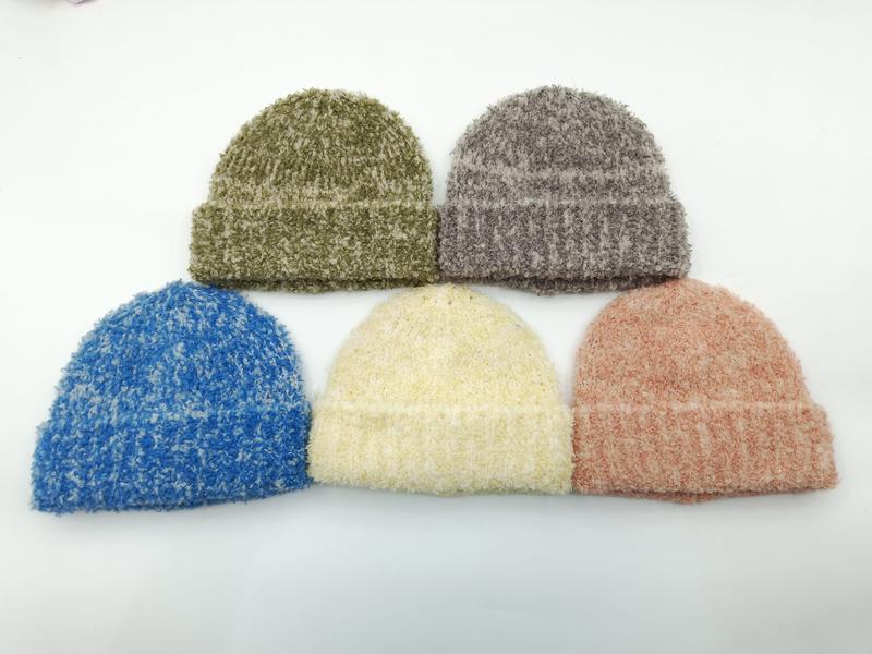 Pięć czapek beanie z bouclé w kolorach: oliwkowym, szarym, niebieskim, kremowym i różowym na białym tle.
