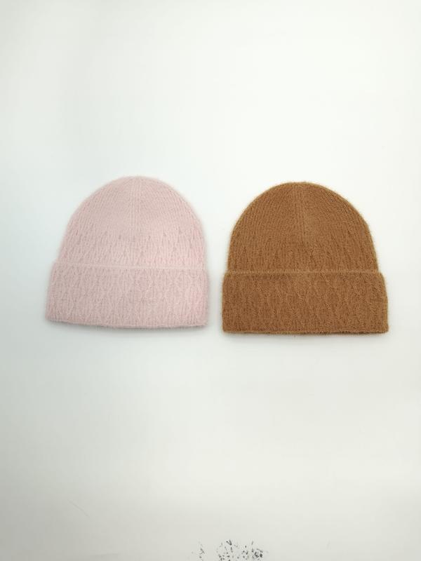 Dwie puszyste czapki beanie z dzianiny: różowa i camelowa, złożone mankiety, na białym tle.