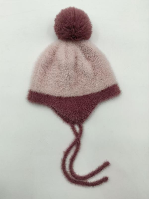 Różowa puchata czapka zimowa z nausznikami, pomponem i wiązaniami, w kolorze dusty pink i ciemnego mauve.