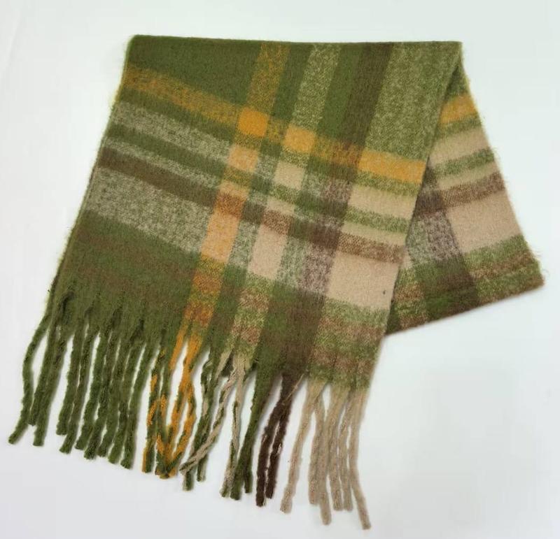Złożony szalik w zieloną kratę z frędzlami, wełniana mieszanka, wzór tartan, białe tło.