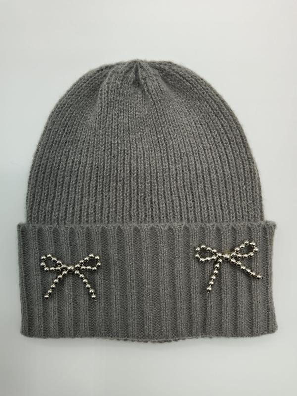 Szara prążkowana czapka zimowa typu beanie z dwoma srebrnymi kokardkami zdobionymi koralikami na mankiecie.