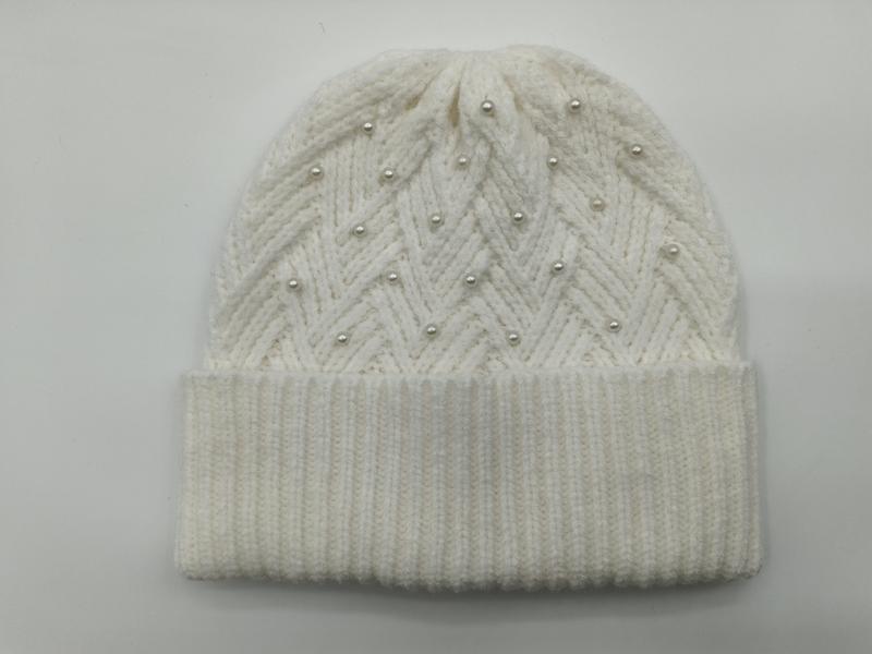 Kremowa czapka beanie z grubego splotu, wzorem chevron w zygzaki i perłowymi koralikami, z podwiniętym brzegiem.
