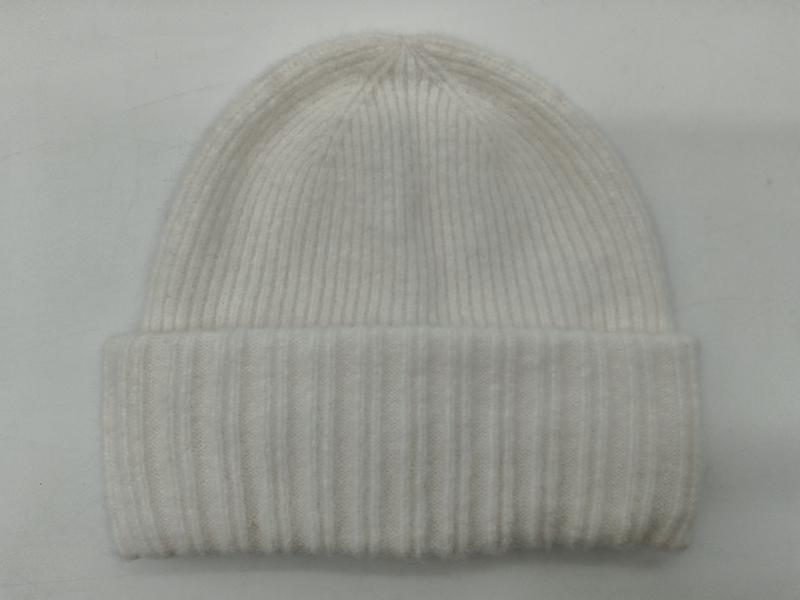 Kremowa czapka beanie z prążkowanej dzianiny z podwiniętym mankietem, miękka wełniana mieszanka, zdjęcie na białym tle.