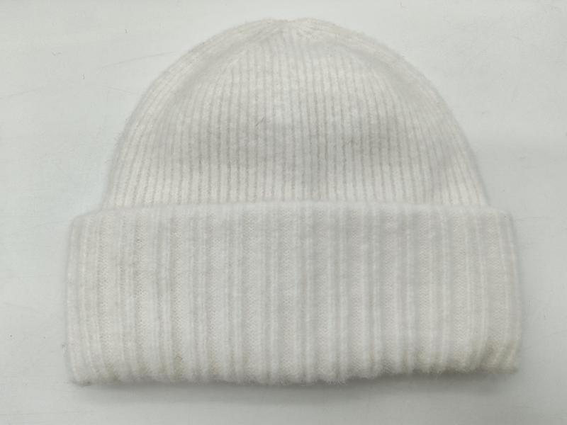 Kremowa prążkowana czapka zimowa typu beanie z podwiniętym mankietem, prezentowana na białym tle.
