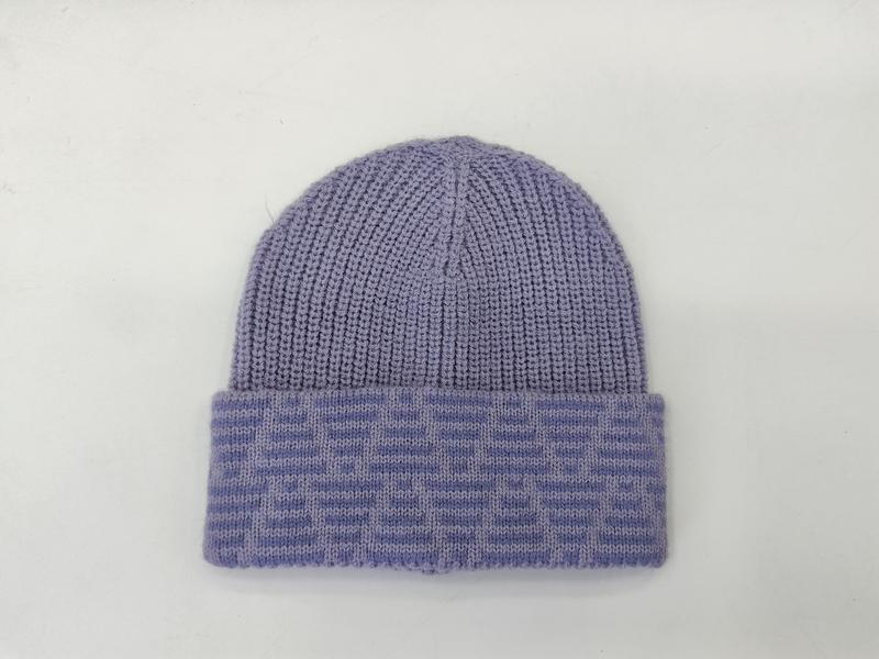 Lawendowa czapka beanie z prążkowanej dzianiny z kontrastowym żakardowym mankietem na białym tle.