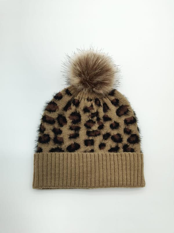 Beżowa czapka beanie w panterkę z puszystym pomponem ze sztucznego futra, na białym tle.