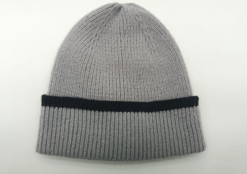 Jasnoszara prążkowana czapka beanie z podwiniętym mankietem z czarnym kontrastowym paskiem, na białym tle.