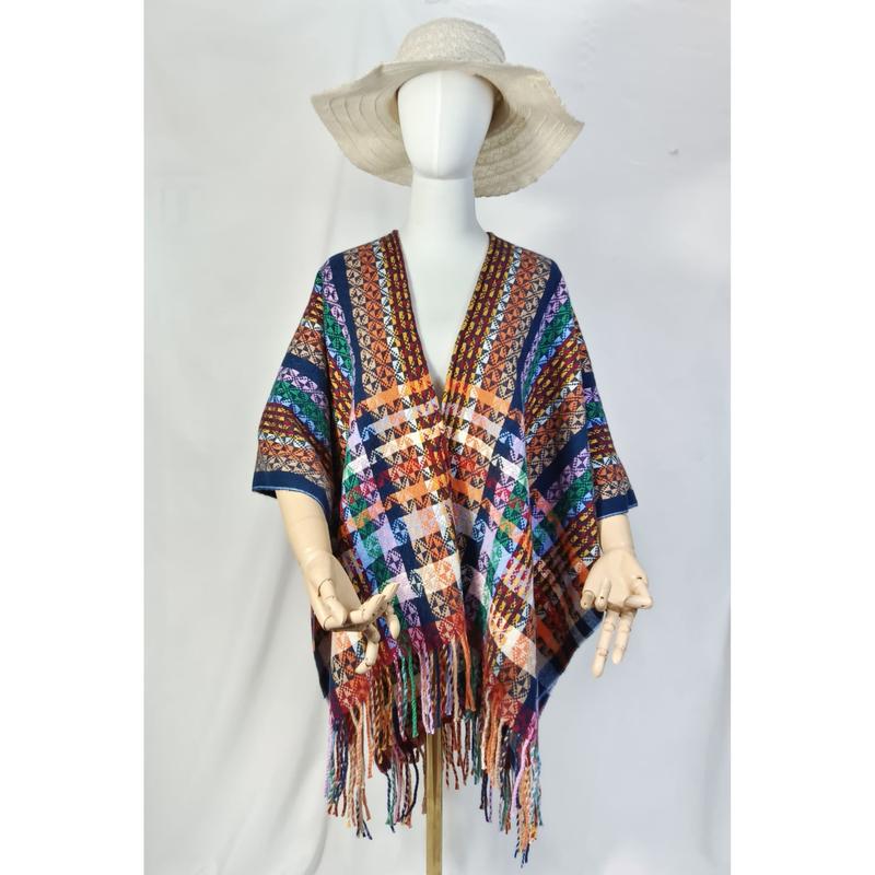 Manekin w kolorowym ponczo boho aztec z geometrycznym wzorem i frędzlami, kremowy kapelusz, białe tło.