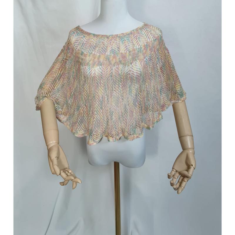 Wielokolorowy pastelowy top poncho typu crop z ażurowym splotem na manekinie z drewnianymi ramionami.
