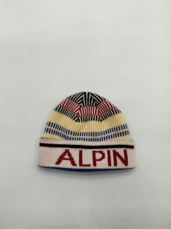 Kolorowa czapka beanie w czerwono-żółto-niebiesko-czarne paski z napisem ALPIN na białym ściągaczu.
