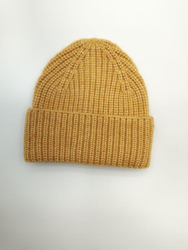 Musztardowa czapka beanie z grubym prążkowanym splotem i podwiniętym mankietem, widok z góry na białym tle.