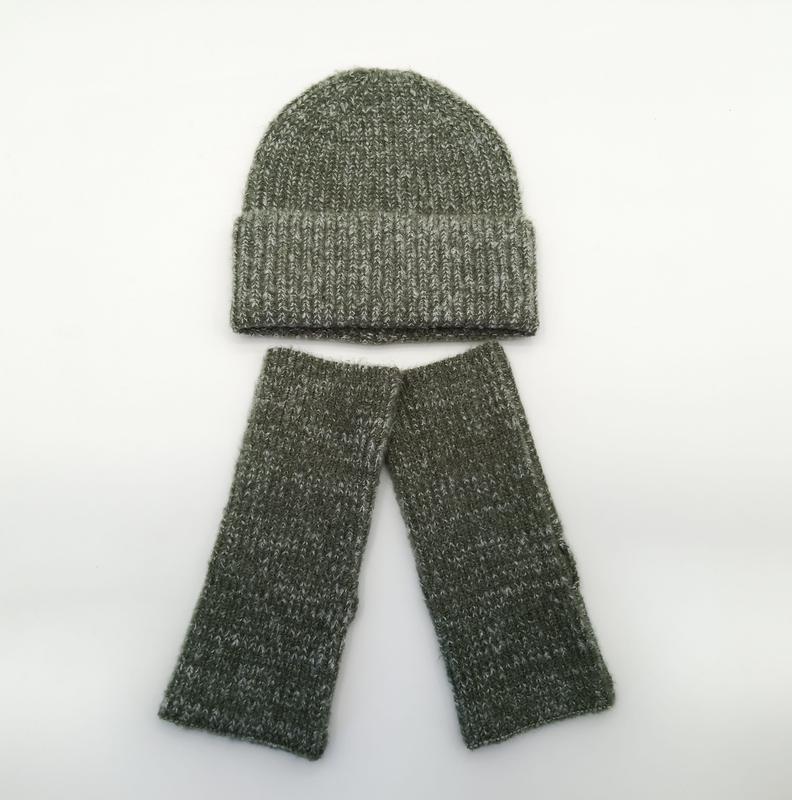 Oliwkowy melanżowy komplet: czapka beanie i rękawiczki bez palców z prążkowanej dzianiny na białym tle.