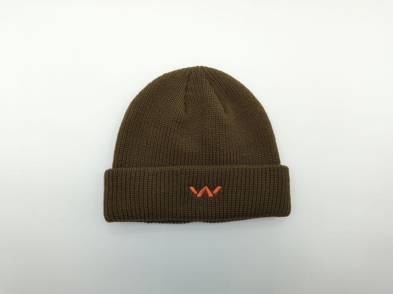 Oliwkowa prążkowana czapka beanie z podwiniętym mankietem i małym pomarańczowym haftowanym logo, na białym tle.