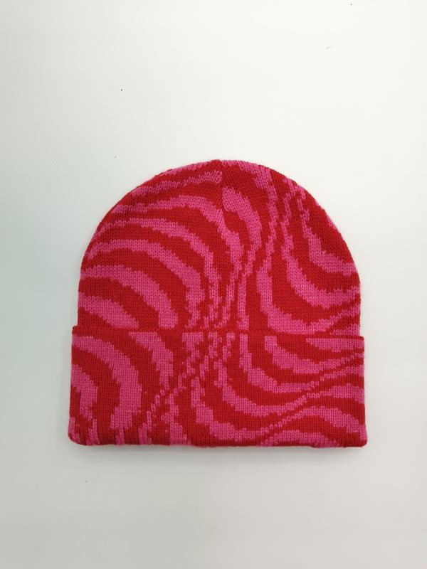 Różowo-czerwona czapka beanie z dzianiny we wzór zebry z podwiniętym rondem, widok z góry na białym tle.
