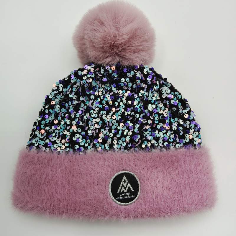 Różowa zimowa czapka beanie z cekinami, futrzanym mankietem i dużym pomponem na białym tle.