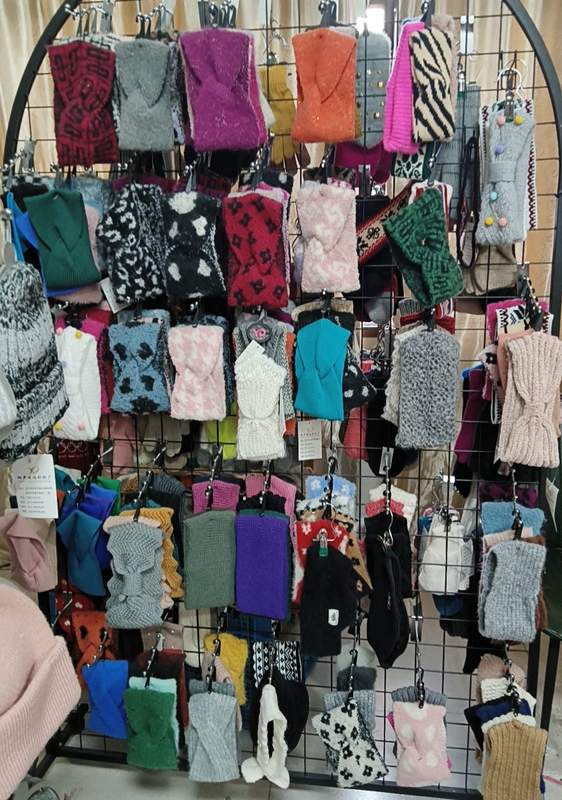 Stojak sklepowy z dzianinowymi rękawiczkami i jednopalczastymi rękawicami zimowymi w różnych kolorach i wzorach.