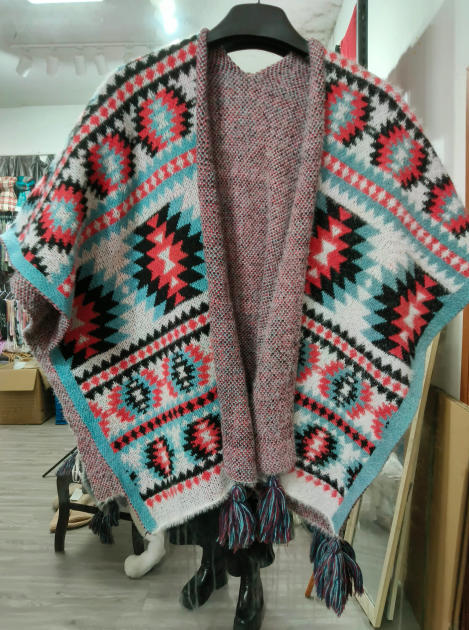 Dzianinowe poncho aztec z geometrycznym wzorem w kolorach czerwonym, turkusowym i czarnym, z frędzlami.