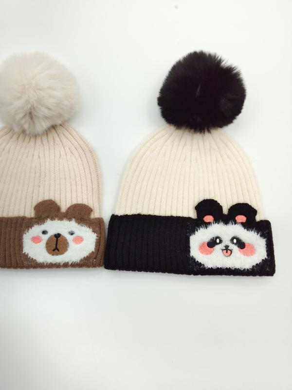 Dwie czapki beanie z pomponem i naszywkami: beżowa z misiem i biała z pandą, prążkowany splot.