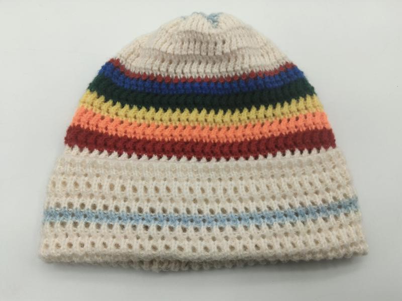 Kremowa czapka beanie z tęczowymi paskami w czerwieni, pomarańczy, żółci, zieleni, błękicie i ażurowym splotem.