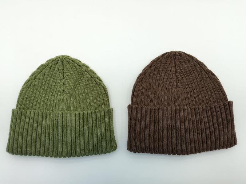 Dwie czapki beanie z prążkowanej dzianiny na białym tle – oliwkowa i brązowa, obie z podwiniętym mankietem.