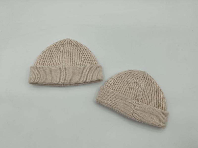 Dwa beżowe prążkowane czapki typu beanie z mankietem, zaprezentowane na białym tle w dwóch rozmiarach.
