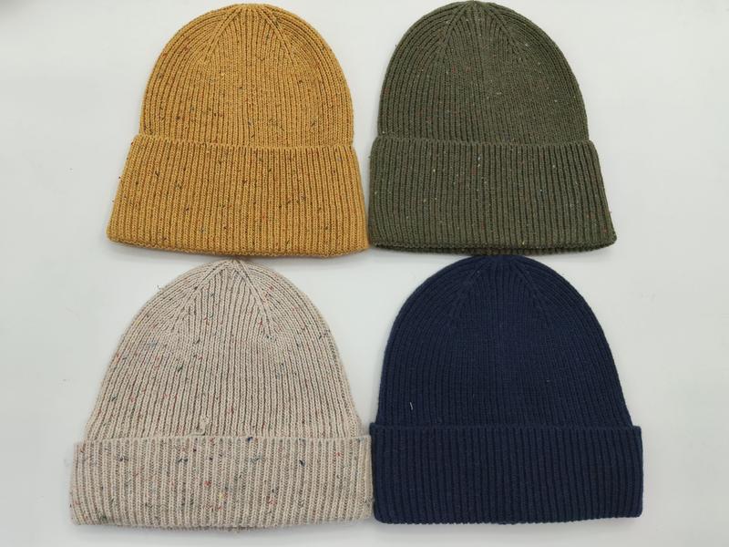 Cztery prążkowane czapki beanie w kolorach musztardowym, oliwkowym, owsianym i granatowym na białym tle.