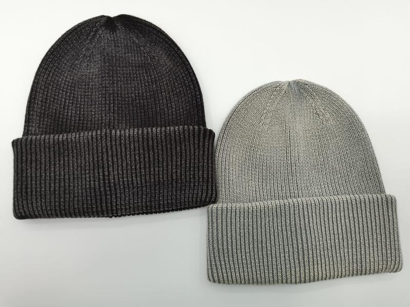 Dwie dzianinowe czapki beanie z mankietem obok siebie: ciemnoszara antracytowa i jasnoszara, na białym tle.