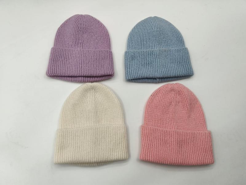 Cztery czapki beanie z prążkowanej dzianiny w pastelowych kolorach: lawendowym, niebieskim, kremowym i różowym.