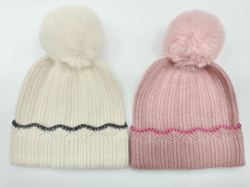 Dwie czapki beanie z pomponem: kremowa z czarnym brokatowym wykończeniem i różowa z różowym brokatem, pompony ze sztucznego futra.